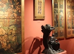 Ściana z zawieszonymi obrazami, a przed nią dwie nieduże rzeźby