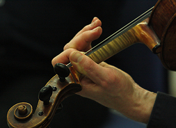 Główka skrzypiec z ułożoną na niej dłonią muzyka