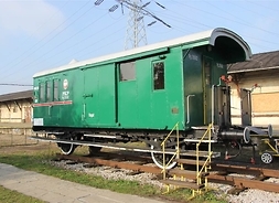 Stary wagon odstawiony na końcówce bocznicy kolejowej. W tle niskie zabudowania muzeum