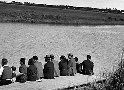 Grupa osób siedząca na pomoście nad rzeką