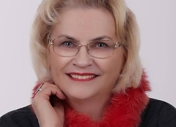 Zdjęcie przedstawia uśmiechniętą kobietę w okularach