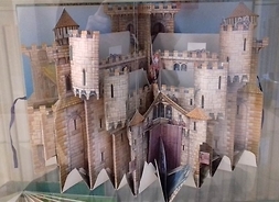 Otwarta książka, przedstawiająca warowny zamek