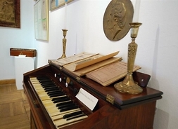 Instrument muzyczny, na którym leżą książki i stoją dwa świeczniki