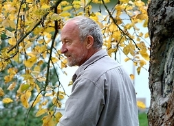 Zdjęcie przedstawia artystę Antoniego Pastwę na tle drzew