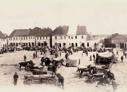Zdjęcie archiwalne z 1916 r., przedstawiające rynek w Wyszogrodzie, stojące na rynku furmanki, stragany, grupę ludzi