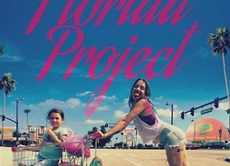 Plakat filmu The Florida Project. Nastolatka pcha przed sobą po ulicy sklepowy wózek, w którym siedzi kilkuletnia dziewczynka