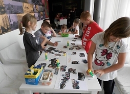 Grupa dzieci wykonująca prace plastyczne. Zdjęcie w pomieszczeniu.