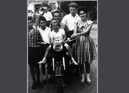 Okładka książki zawierająca archiwalne zdjęcie przedstawiające grupę młłodzieży pozującą do fotografii. Pośrodku na motorze siedzi uśmiechnięta dziewczynka a za nią chłopiec.