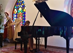 Dziewczyna grająca na fortepianie w sali muzealnej.