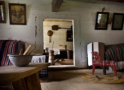 Wnętrze wiejskiej izby, z tradycyjnymi sprzętami codziennego użytku.