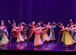 Tancerze zespołu Mazowsze w strojach scenicznych tańczą na scenie.