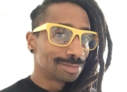 Afroamerykanin z wąsami i dredami, w okularach. Zdjęcie portretowe
