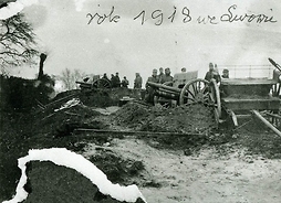 Fotografia archiwalna przedstawiająca grupę żołnierzy stojących przy działach.