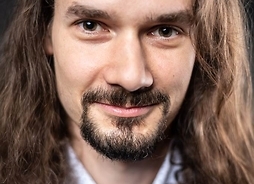 Uśmiechnięty mężczyzna z długimi włosami, wąsami i brodą, zdjęcie portretowe.