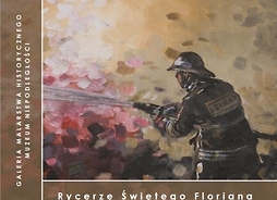 Okładka książki zawierająca fragmentu obrazu przedstawiającego strażaka w munudrze i ochronnym hełmie gaszącego ogień wodą ze strażackiego węża.