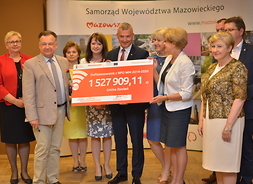 Beneficjenci i przedstawiciele zarządu województwa mazowieckiego z symbolicznym czekiem