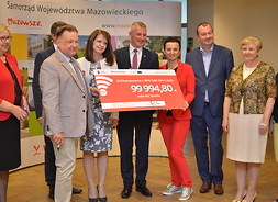 Przedstawiciele zarządu województwa mazowieckiego i beneficjent z symbolicznym czekiem
