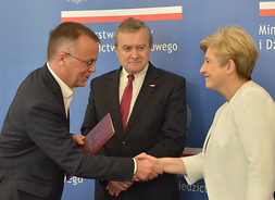 Wiceminister Jarosław Sellin gratuluje członek zarządu Elżbiecie Lanc. W środku stoi minister Piotr Gliński