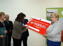 Wicemarszałek Janina Ewa Orzełowska podpisuje symboliczny czek trzymany przez członek zarządu Elżbietę Lanc