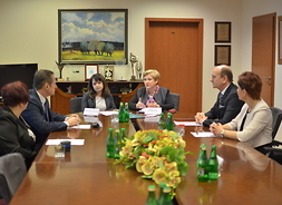 Beneficjenci, wicemarszałek Janina Ewa Orzełowska i członek zarządu województwa mazowieckiego Elżbieta Lanc omawiają umowy przy stole konferencyjnym