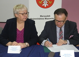 Marszałek Adam Struzik (po lewej) podpisuje umowę, po lewej siedzi Elżbieta Szymanik zastępca dyrektora Mazowieckiej Jednostki Wdrażania Programów Unijnych