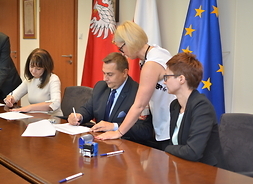 Wicemarszałek Janina Ewa Orzełowska i beneficjenci podpisują umowę