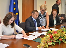 Wicemarszałek Janina Ewa Orzełowska i beneficjenci podpisują umowę