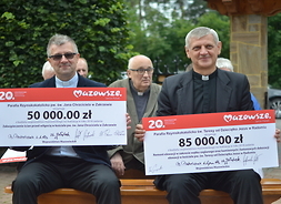 Księża z parafii, które otrzymały dofinansowanie prezentują symboliczne czeki