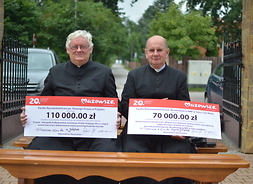 Księża z parafii, które otrzymały dofinansowanie prezentują symboliczne czeki