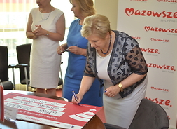 Członek zarządu Elżbieta Lanc podpisuje czek