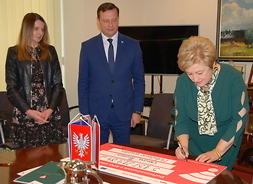 Członek zarządu województwa mazowieckiego ELżbieta Lanc podpisuje czek