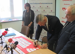 Członek zarządu Rafał Rajkowski podpisuje symboliczny czek